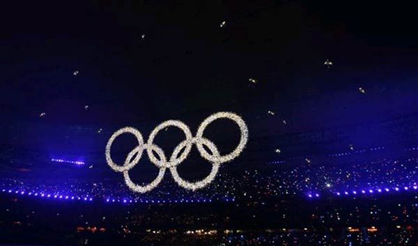 Olympics rings glitter over performers inside the stadium.